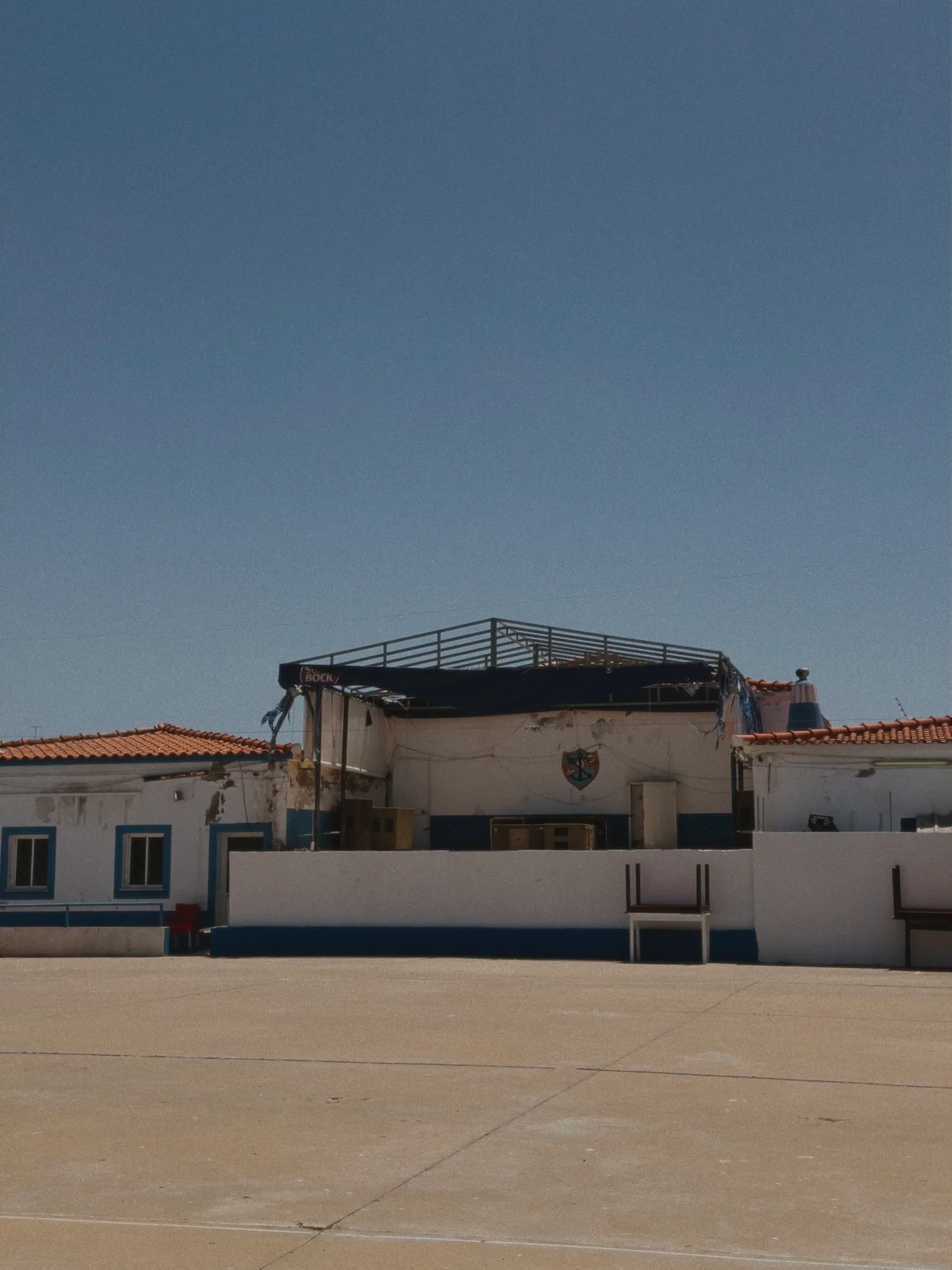 The weathered white and blue exterior of CUC, Culatra's local club, beneath a large empty sky.