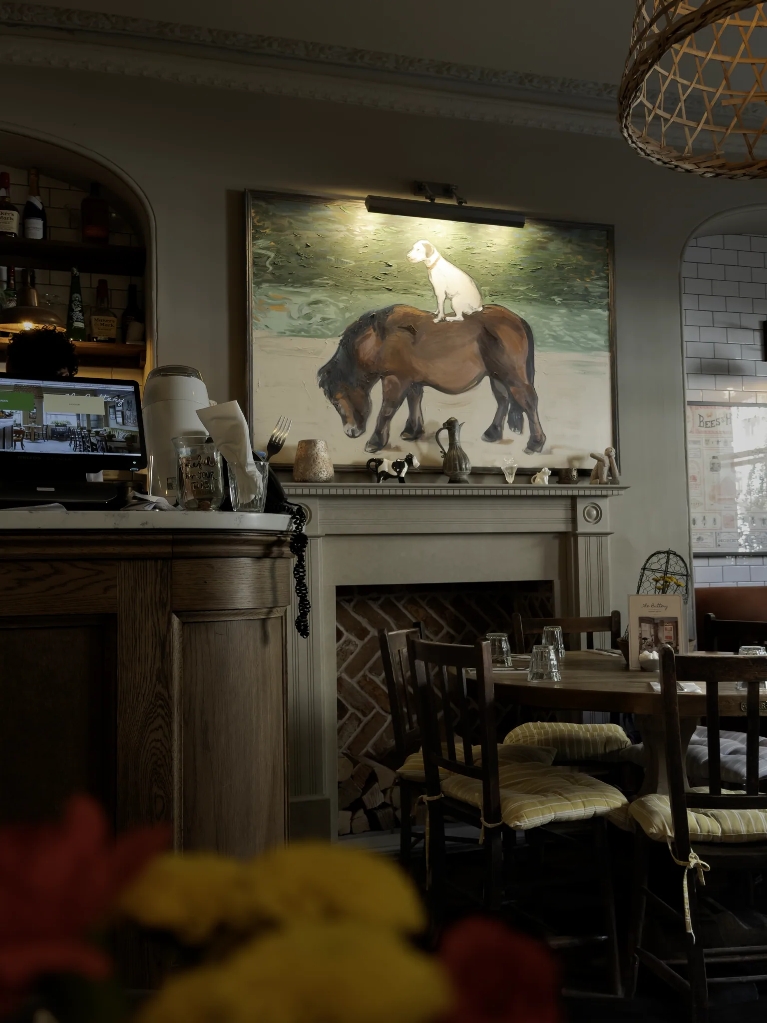 The Buttery’s dining room with dark wooden furniture, a fireplace and a large painting of a dog standing on a horse.